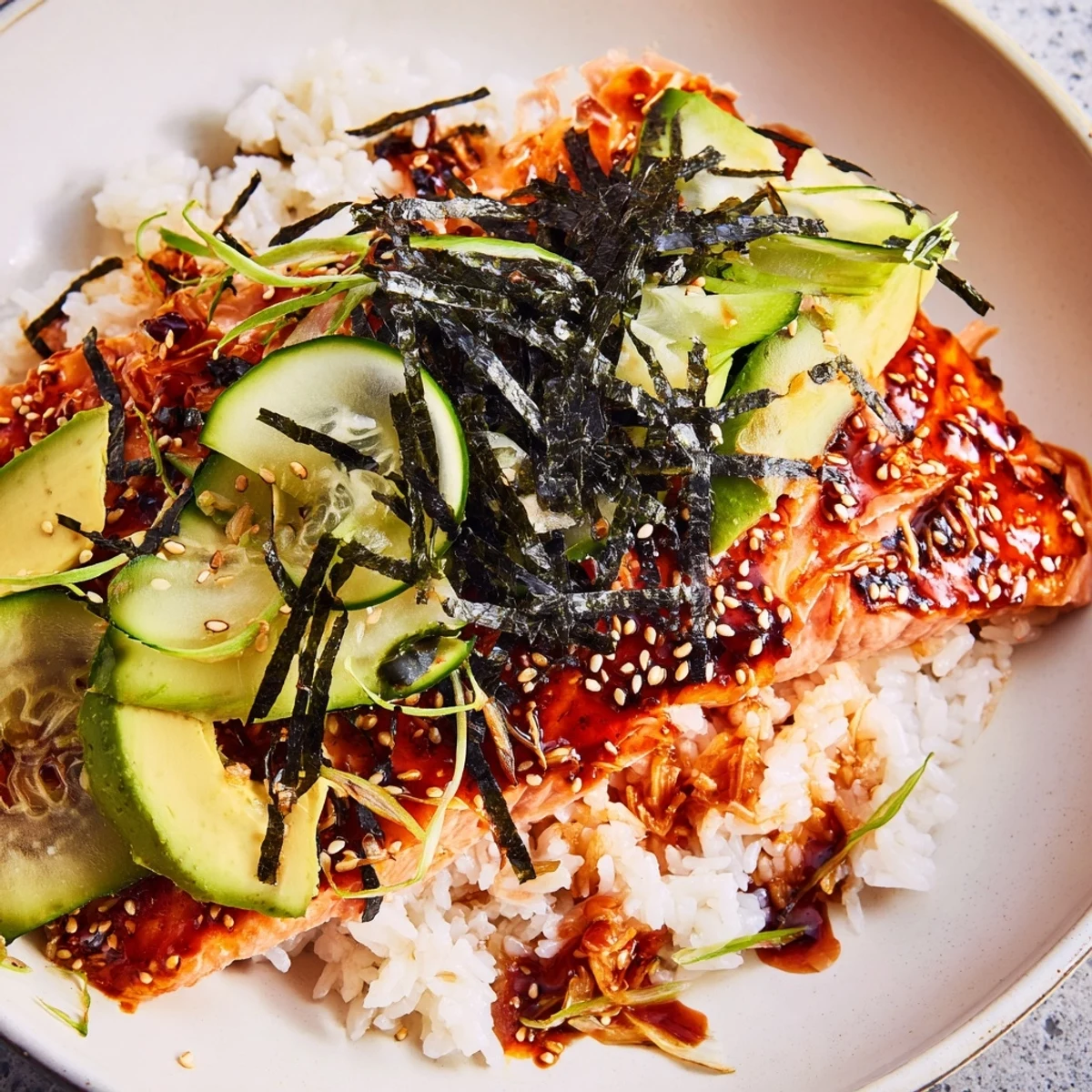 Emily Mariko-inspired gochujang salmon bowl with glistening, glazed salmon next to vibrant toppings.