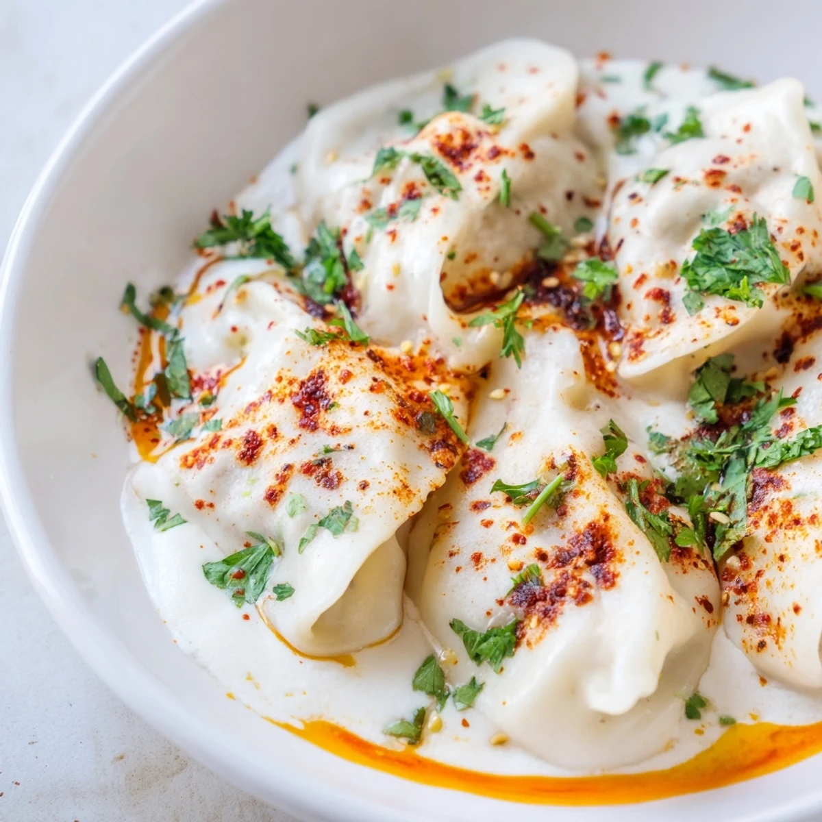 Steaming plate of Turkish cheesy manti, with creamy cheese filling, ready to enjoy this delightful dish.