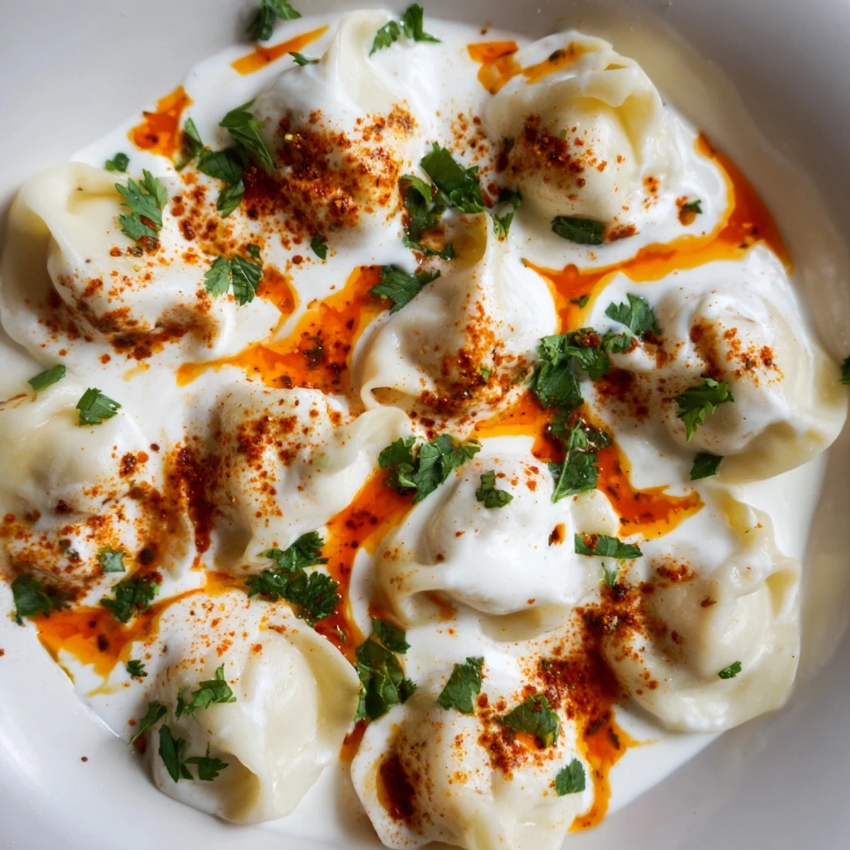 Savory Turkish cheesy manti presentation: bite-sized dumplings, beautifully plated with yogurt and spice.