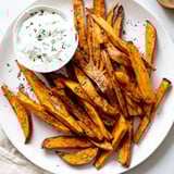 Golden, perfectly baked sweet potato fries, ready to dip into fresh herbed yogurt for a delicious side.