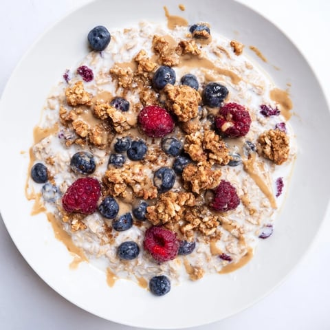 Creamy Overnight Oats Gourmet Makeover topped with berries, granola, and a nut butter swirl.