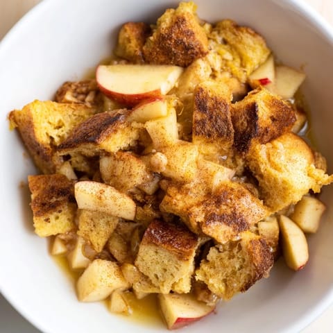 Rustic bread pudding with apples featuring cinnamon, perfect for a cozy fall gathering.