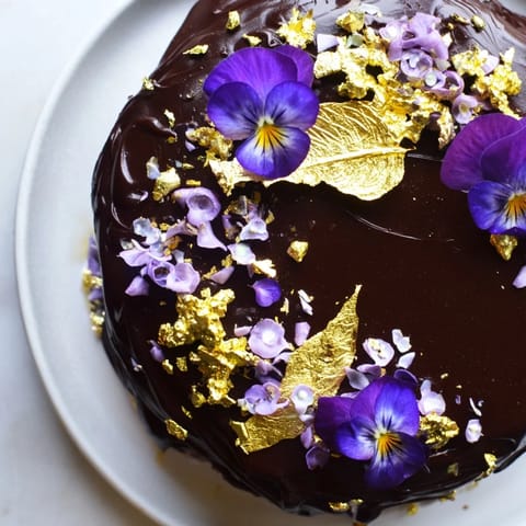 Dieser Wild Rat Cake, kunstvoll drapiert mit Gold, zeigt die reiche Schokoladenglasur und zarte Dekorationen.