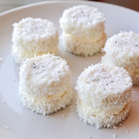 A close-up of delicate Snowball Tea Sandwich Bites coated in white coconut for the holiday.