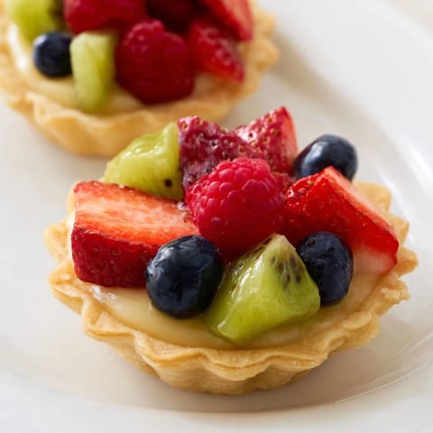 Freshly baked Mini Fruit Tartlets boasting a lovely circle fruit arrangement for a tasty dessert idea.