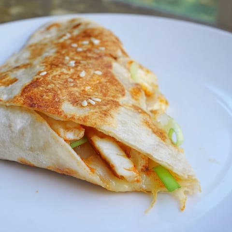 Warm, crispy-edged Korean BBQ Chicken Wrap Grilled Cheese with sesame seeds and scallions, ready to eat.