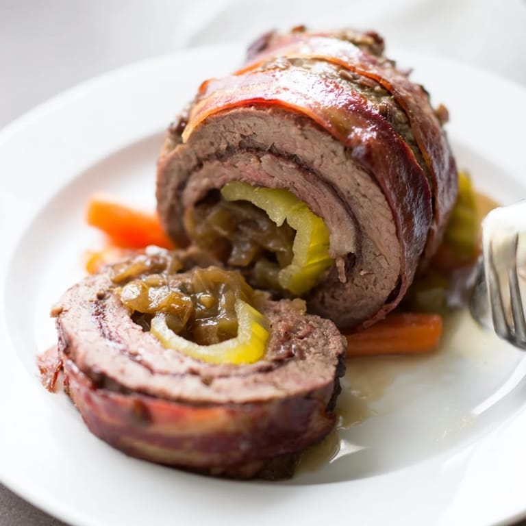 Saftige Rinderrouladen mit Zwiebeln, serviert mit Kartoffelknödeln und Gravy.