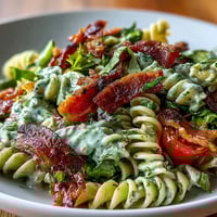 Ein farbenfroher Sommersalat mit Pasta, knusprigem Speck, saftigen Tomaten, frischem Salat und cremigem Avocado-Ranch-Dressing – perfekt für Picknicks.
